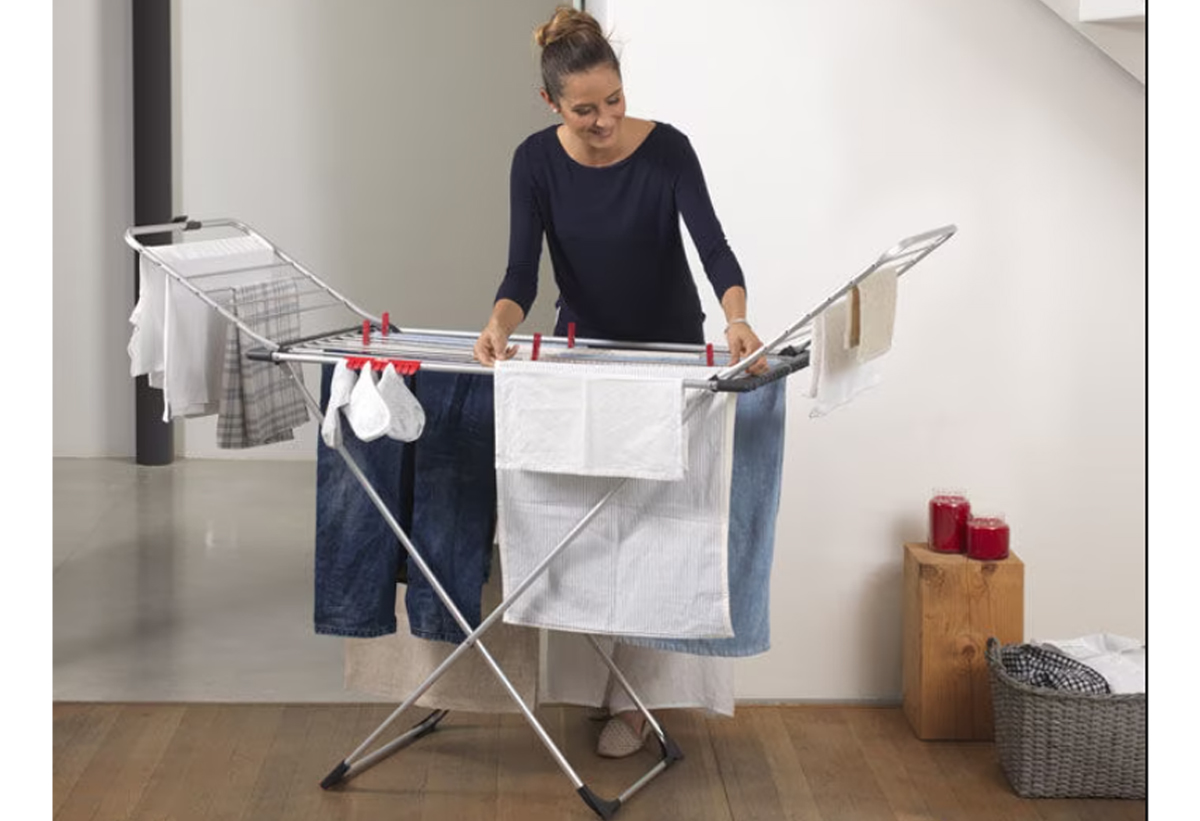 Απεικονίζεται μία γυναίκα να απλώνει τα ρούχα της.